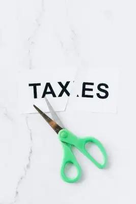 Scissors cutting through a paper with the word taxes on it