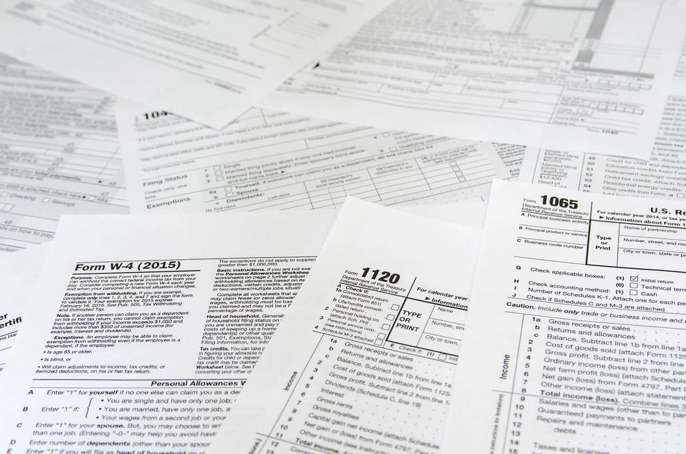 Federal tax forms W-4, 1120 and 1065 on a table
