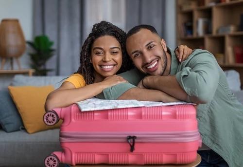 Man and woman smiling while leaning on a suitcase