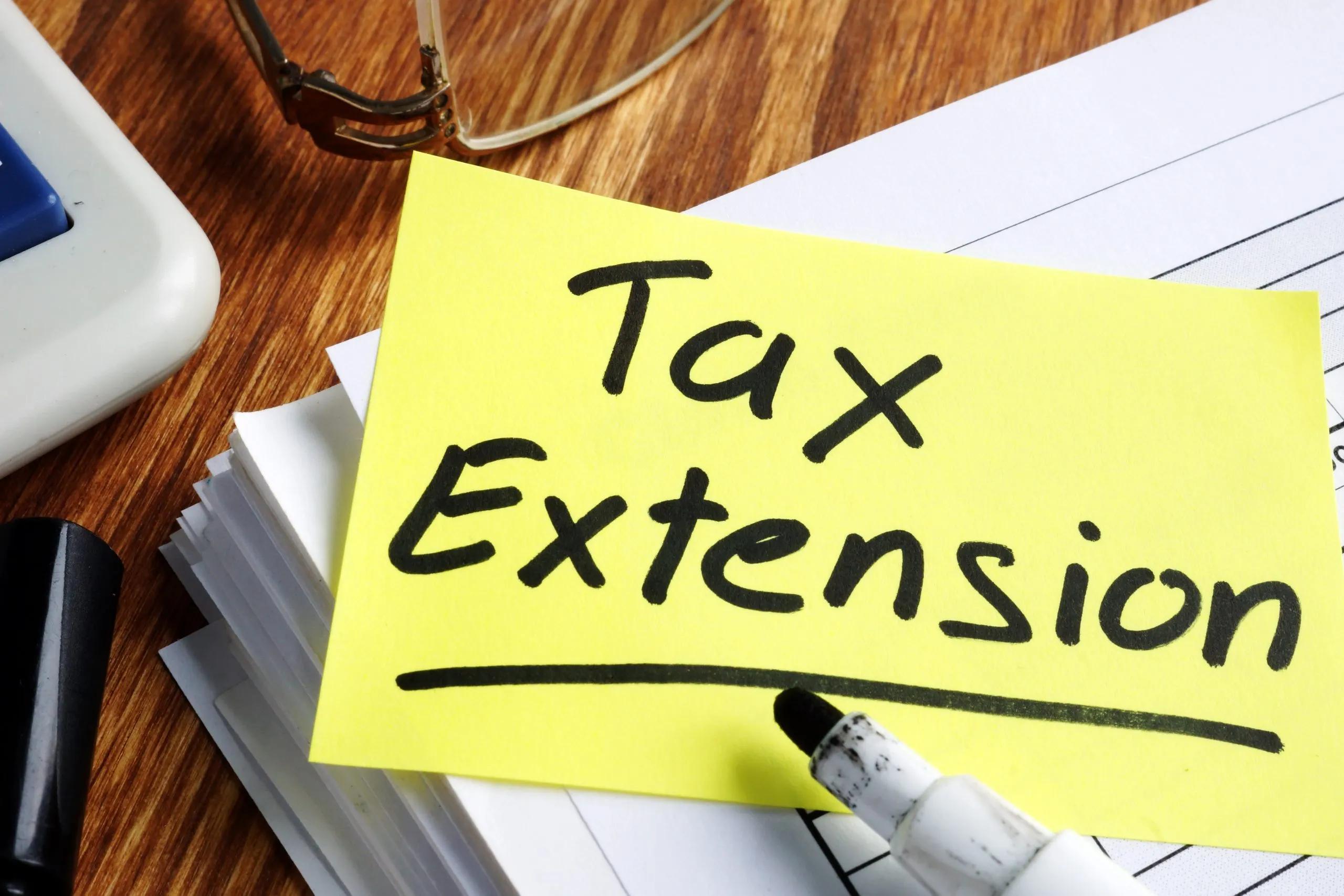 The word "tax extension" written on yellow sticky note